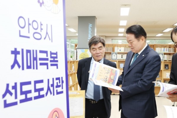 치매 관련 사진2_2025년 4월9일 석수도서관에서 열린 치매극복 선도도서관 지정 현판식에 참석한 최대호 안양시장이 도서를 살펴보고 있다.jpg
